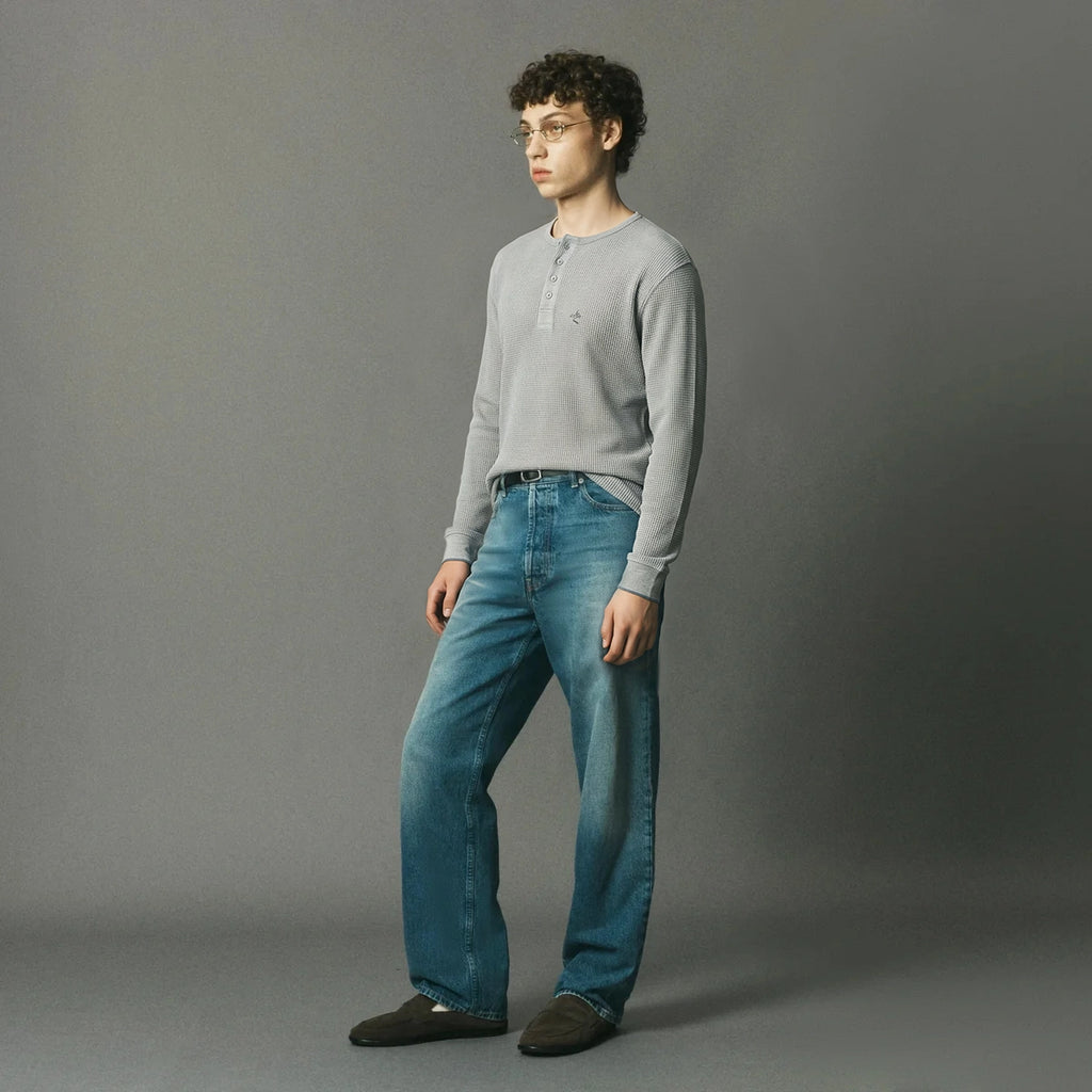 Woven from 100% premium Portuguese cotton, the Long Sleeve Henley is reimagined for FW26 in a grey melange waffle knit.