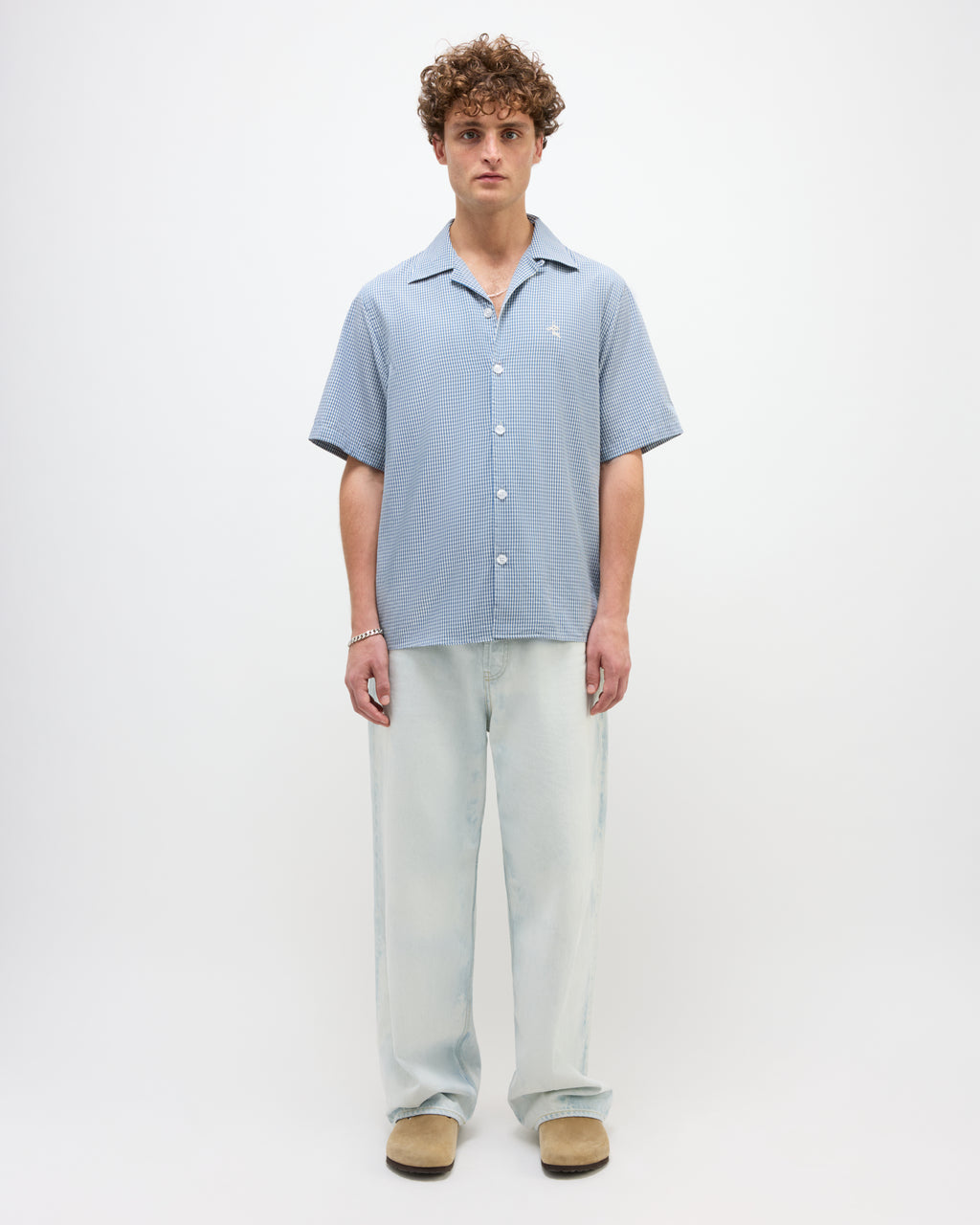 Man wearing a light blue button-up shirt and light gray pants on a white background